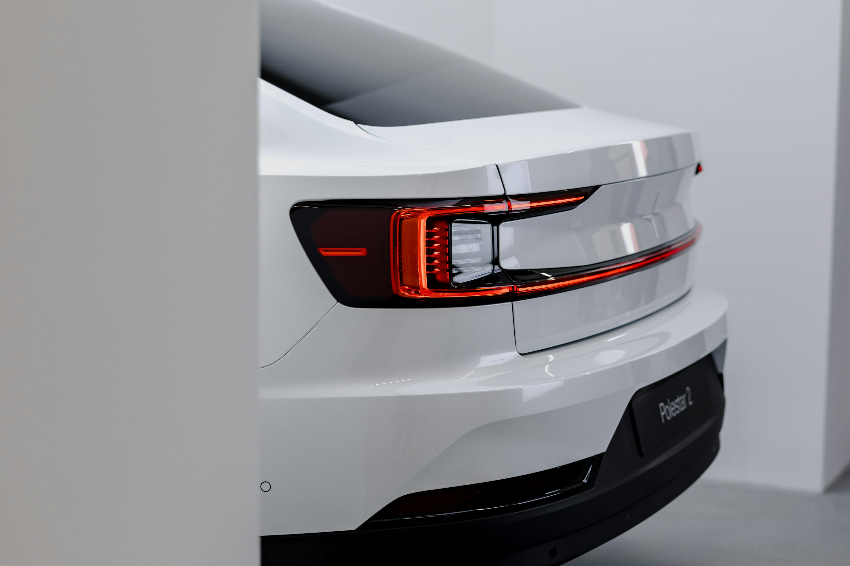 Close crop of the rear light bar and badge of a white Polestar 2